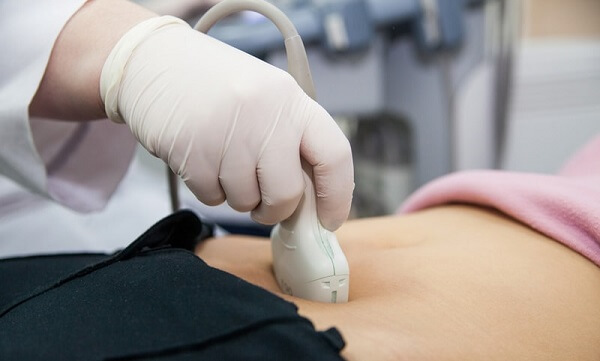 Ultrassom em Curitiba: Na imagem, médico especialista em ultrassonografia realiza o exame na região abdominal da paciente.