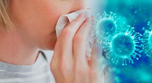 Vacina Influenza em Curitiba: A imagem mostra uma mulher assoando seu nariz, enquanto em sua frente, está uma representação, em tons de azul dos germes que ela está expelindo durante o ato.